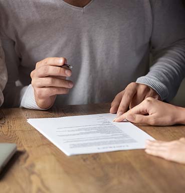 man in sweater signing paperwork for financial planning after divorce